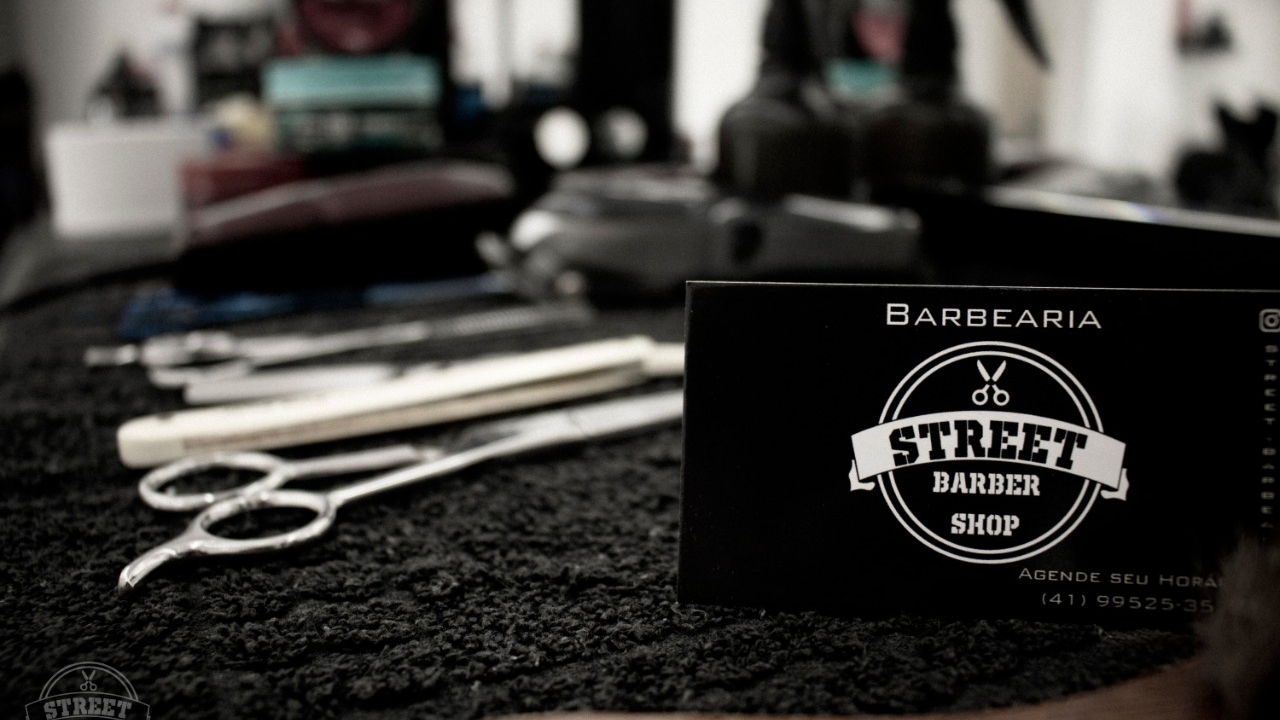 Ferramentas de corte e cartão da Barbearia Street Cut sobre a bancada