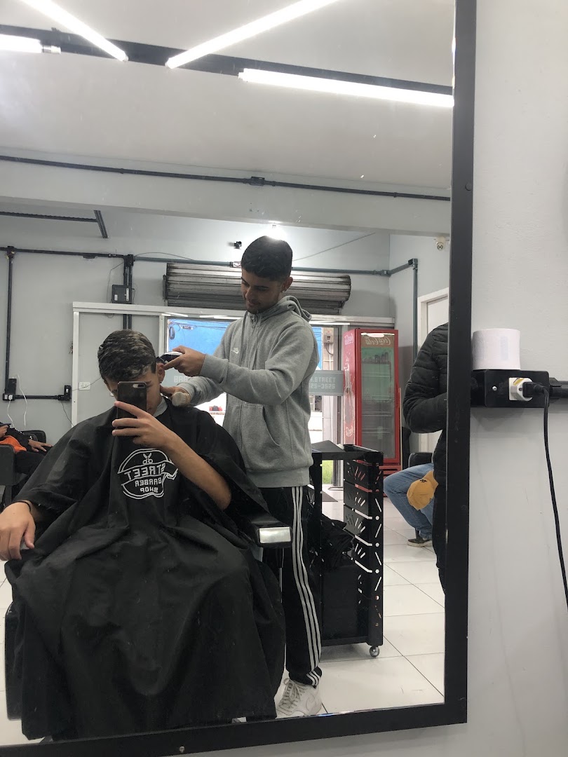 Barbeiro cortando o cabelo de um cliente, refletido no espelho da Barbearia Street Cut